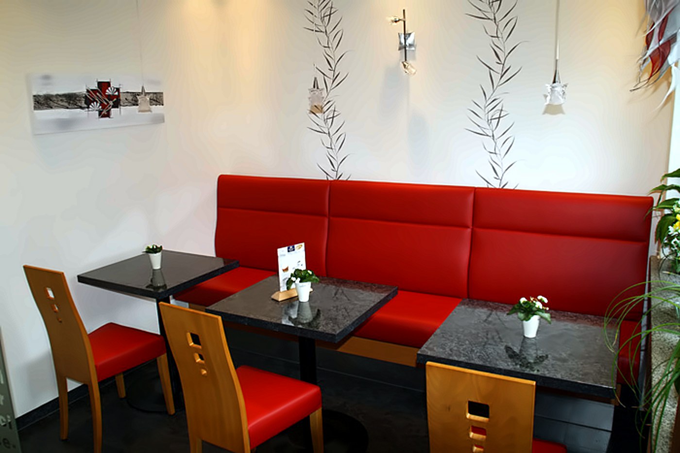 Gemütliche Cafestube mit roter Sitzbank und dunklen Granittischen