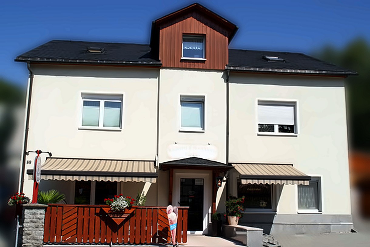 Das Haus der Konditorei und Bäckerei Fiedler mit Markisen und Blumenschmuck