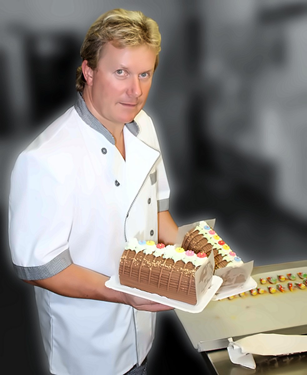Der Konditor präsentiert frisch verzierte Kuchen mit bunten Blüten